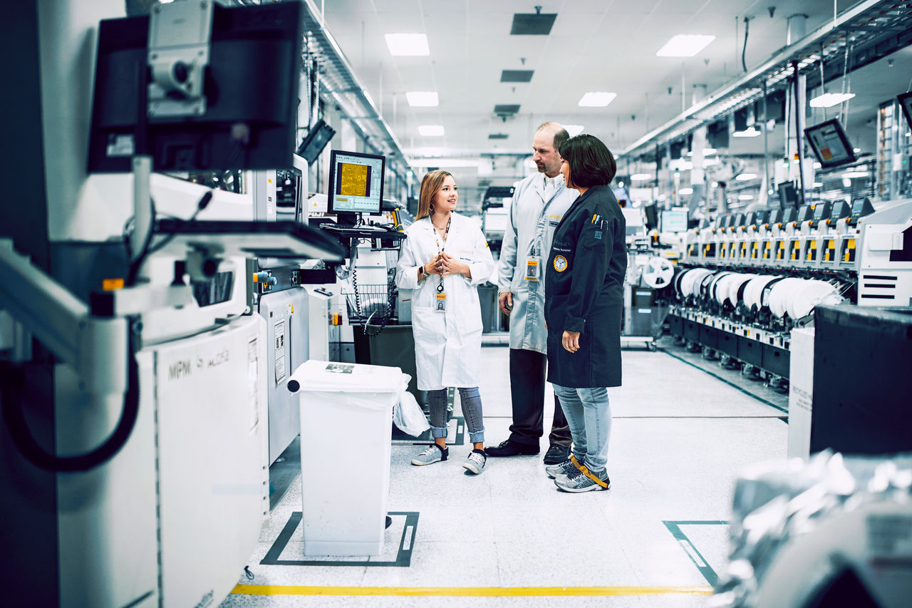 Three people exchanging in a labaroatory about new advancementss