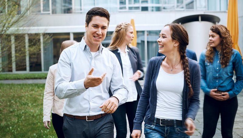 A group of young adults walk smiling through a courtyard