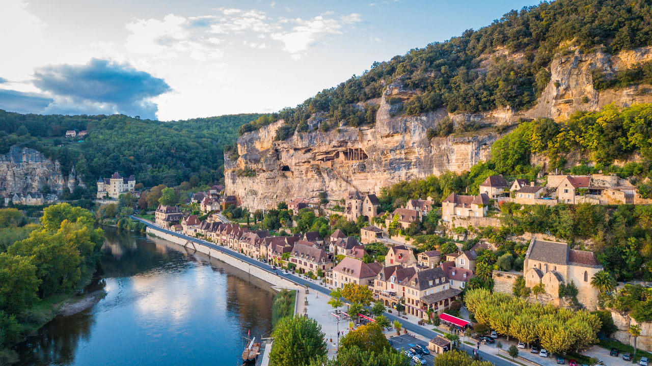 La Roque-Gageac, a picturesque riverside village in southwestern France, nestled beneath towering limestone cliffs and reflected in a calm river.