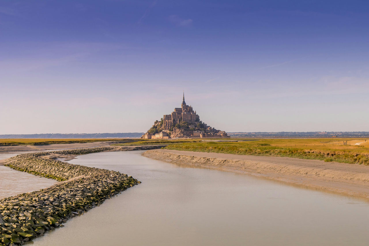Mont-Saint-Michel rises from the tidal flats at the edge of Normandy and Brittany, framed by a tranquil river and wide-open skies. 