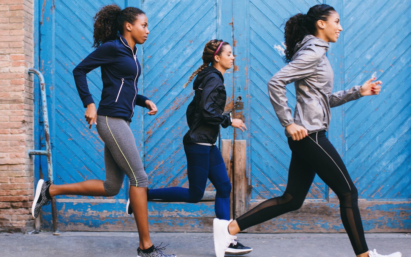 Three women running in front of a warehouse.