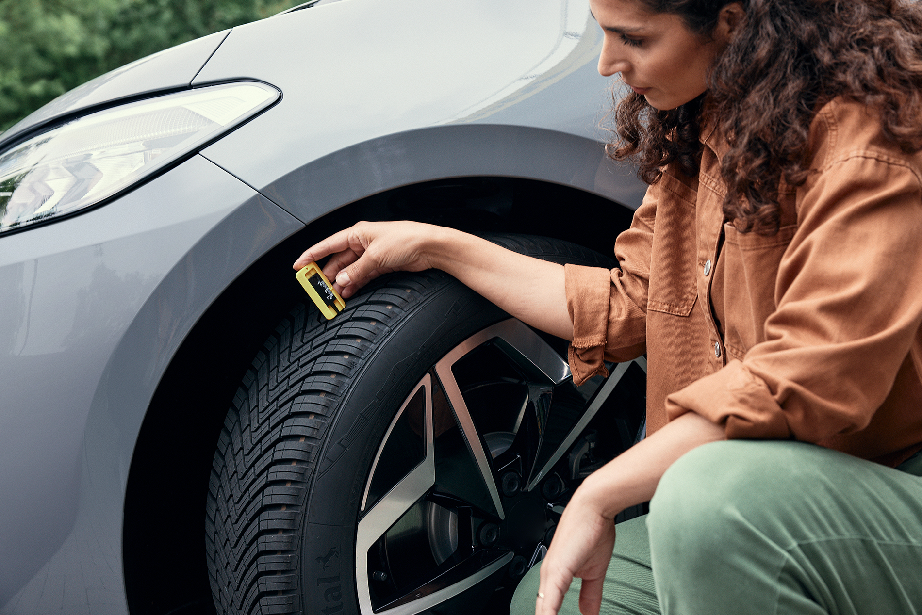 차량의 타이어 트레드 깊이를 확인하는 여성