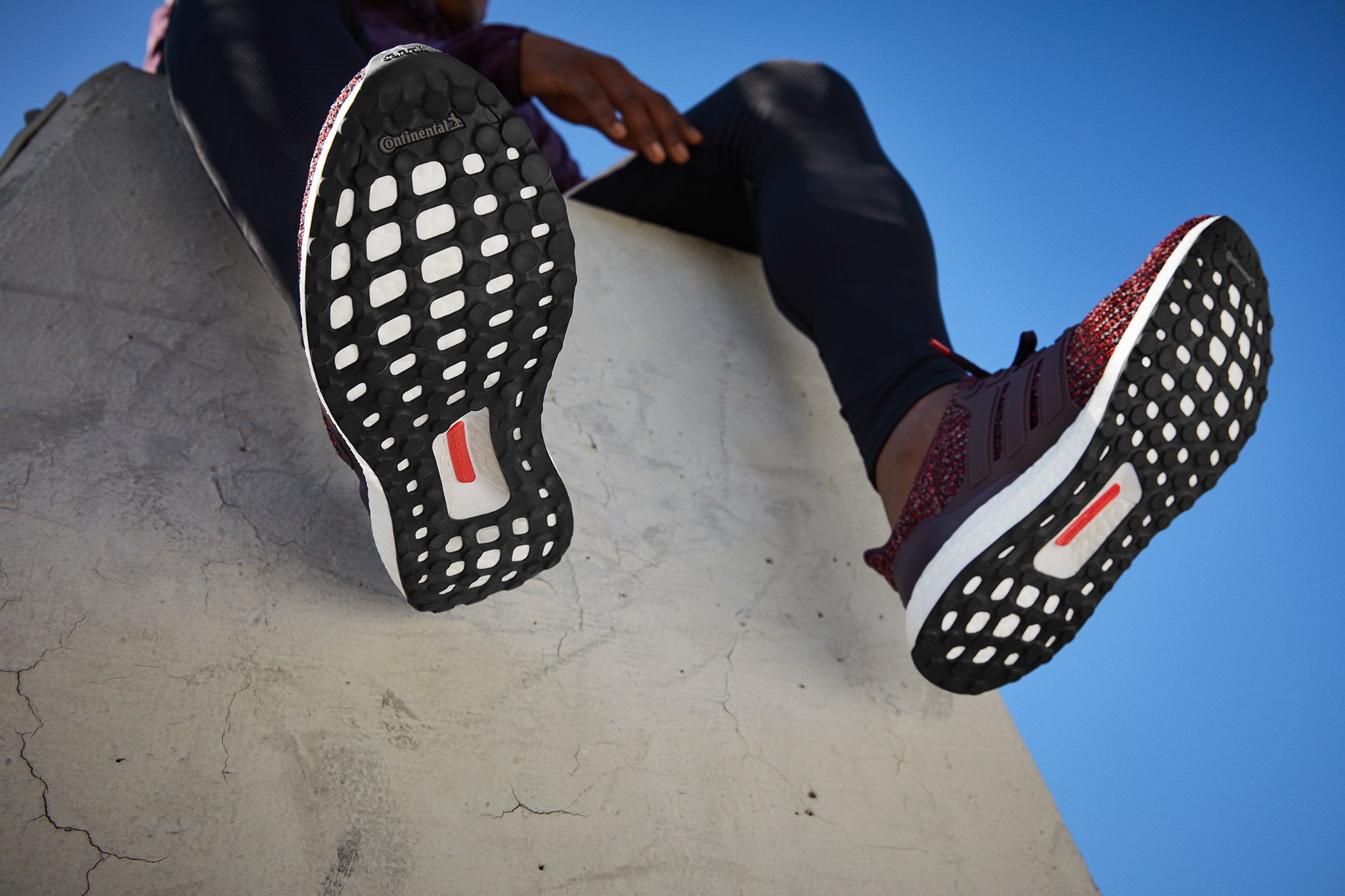 Athlete sitting on a stone with Adidas running shoes.