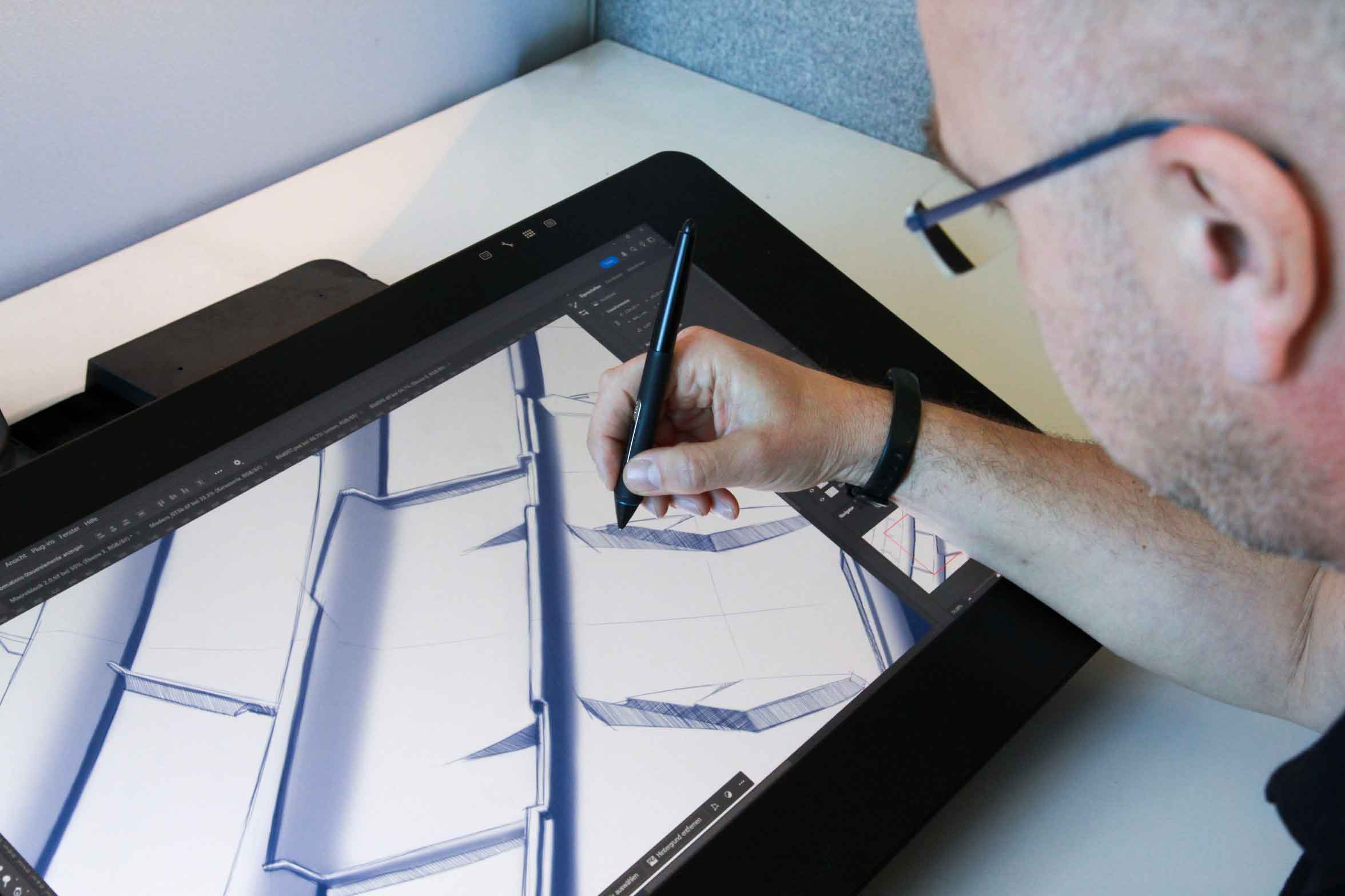 (homem branco, desenvolvedor da Continental Pneus, projetando em uma mesa digital o desenho de uma banda de rodagem especificamente para um determinado requisito)