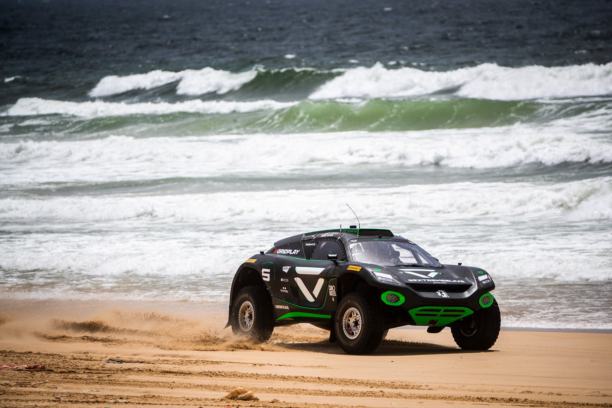 Une voiture de course Extreme E roulant le long de la plage au Sénégal