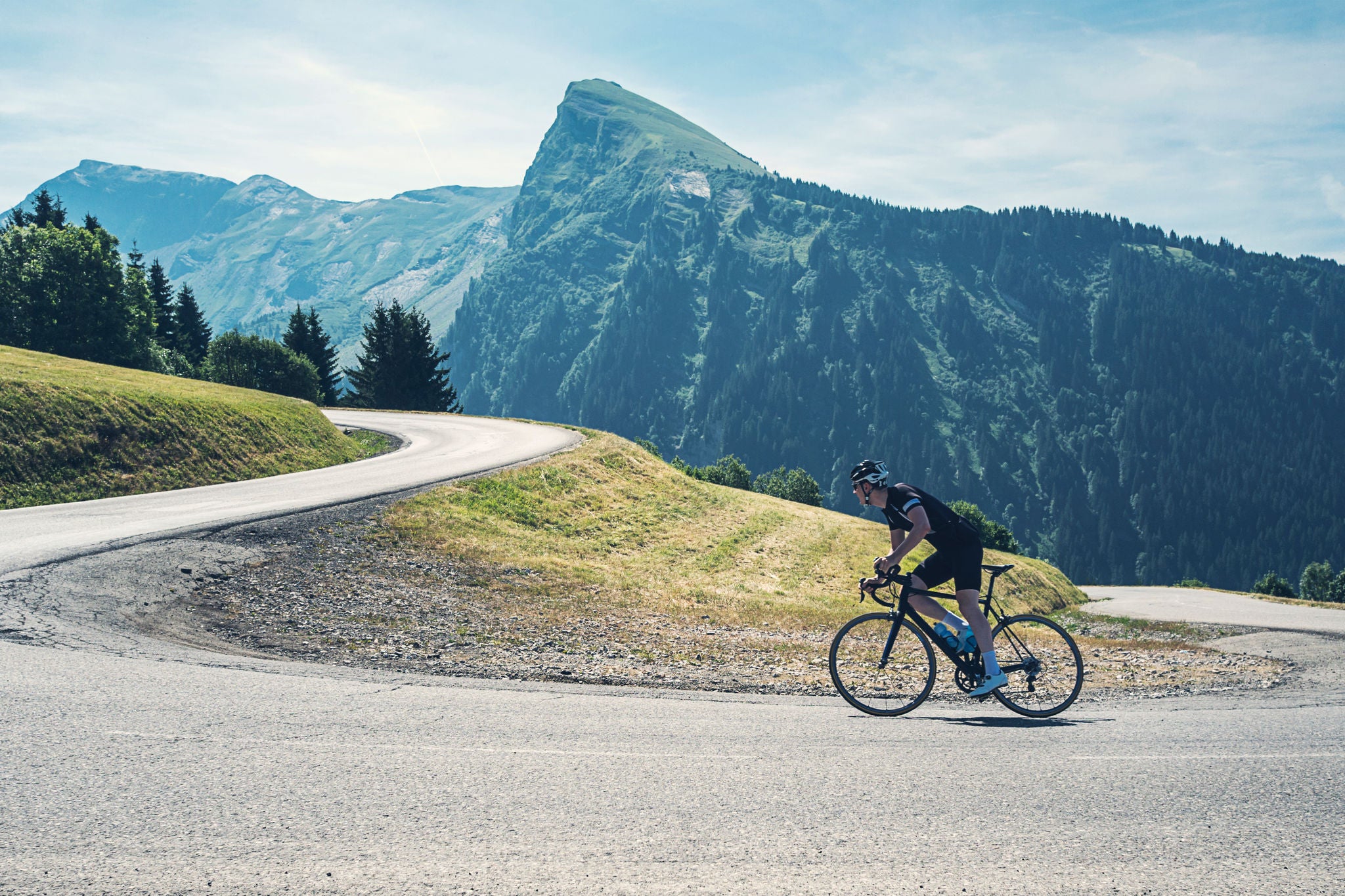 cyclists ride down a hill and take a corner