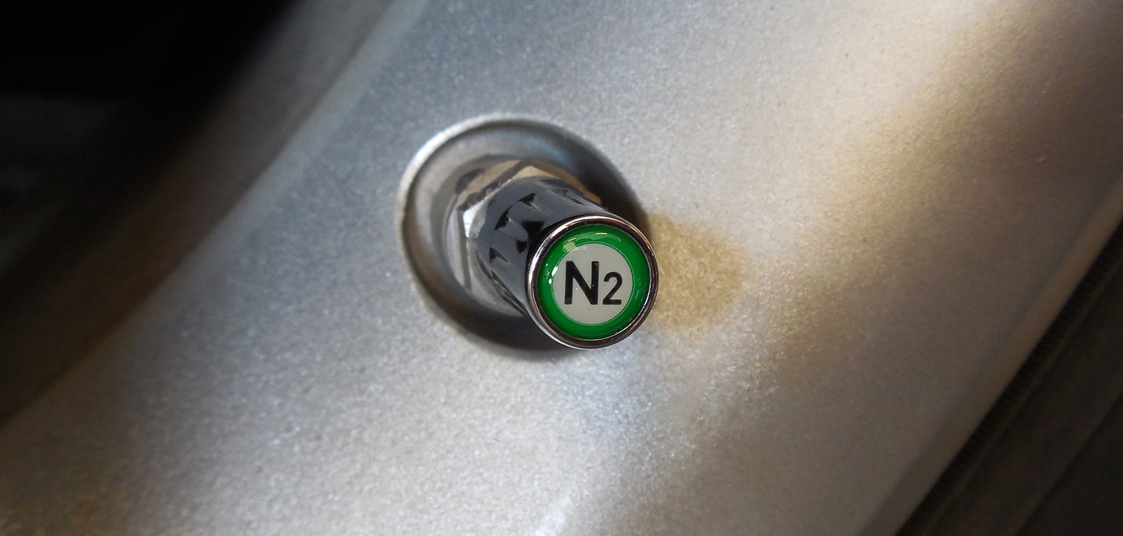 Chrome nitrogen (N2) TPMS-safe valve cap installed on an aluminum TPMS stem in an alloy wheel