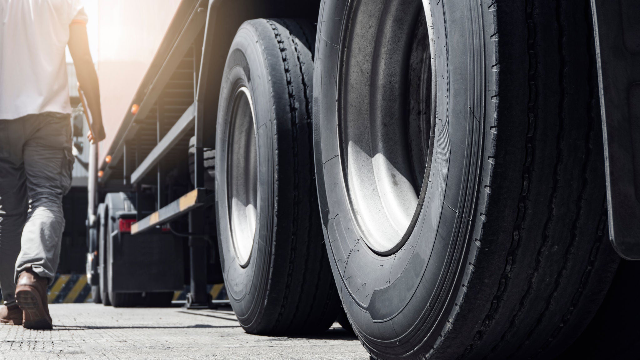 Closeup a truck wheels and a truck driver holding clipboard inspecting safety vehicle maintenance checklist., Closeup a truck wheels and a truck driver holding clipboard insp