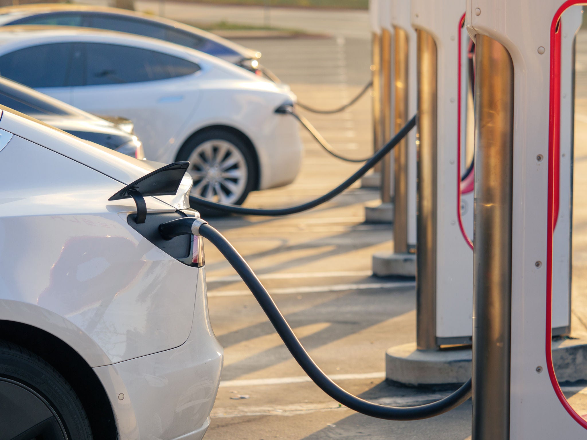 Electric cars charging at charging station outdoors at sunset.