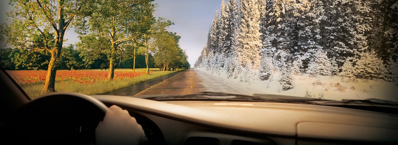 Driving on a road with winter and summer conditions.