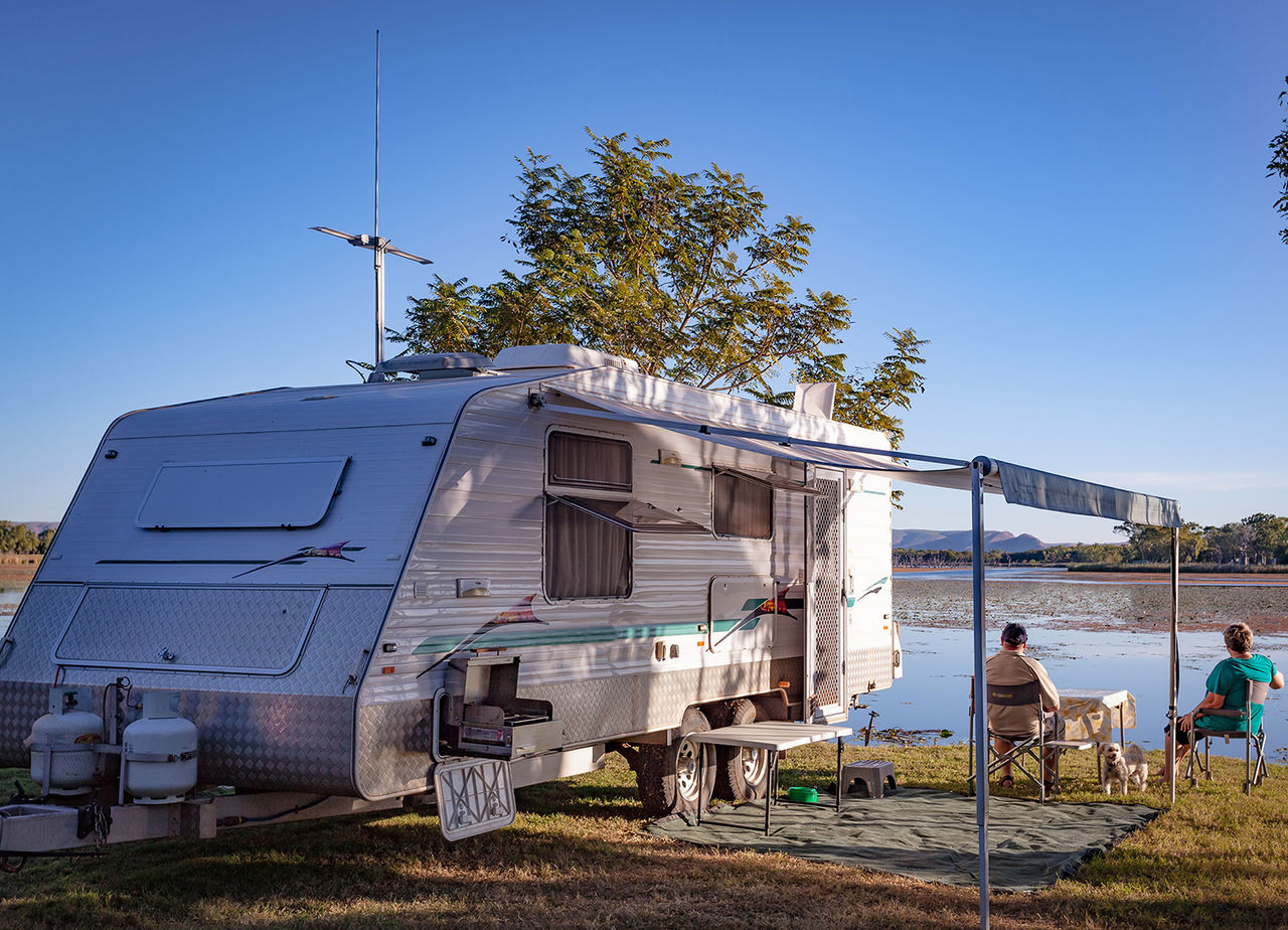 Retired couple with small dog sitting enjoying view to lake next to a modern caravan, Retired couple with small dog sitting enjoying view to lake next A stunning location next to Lake Kununurra in the Kimberley of Western Australia