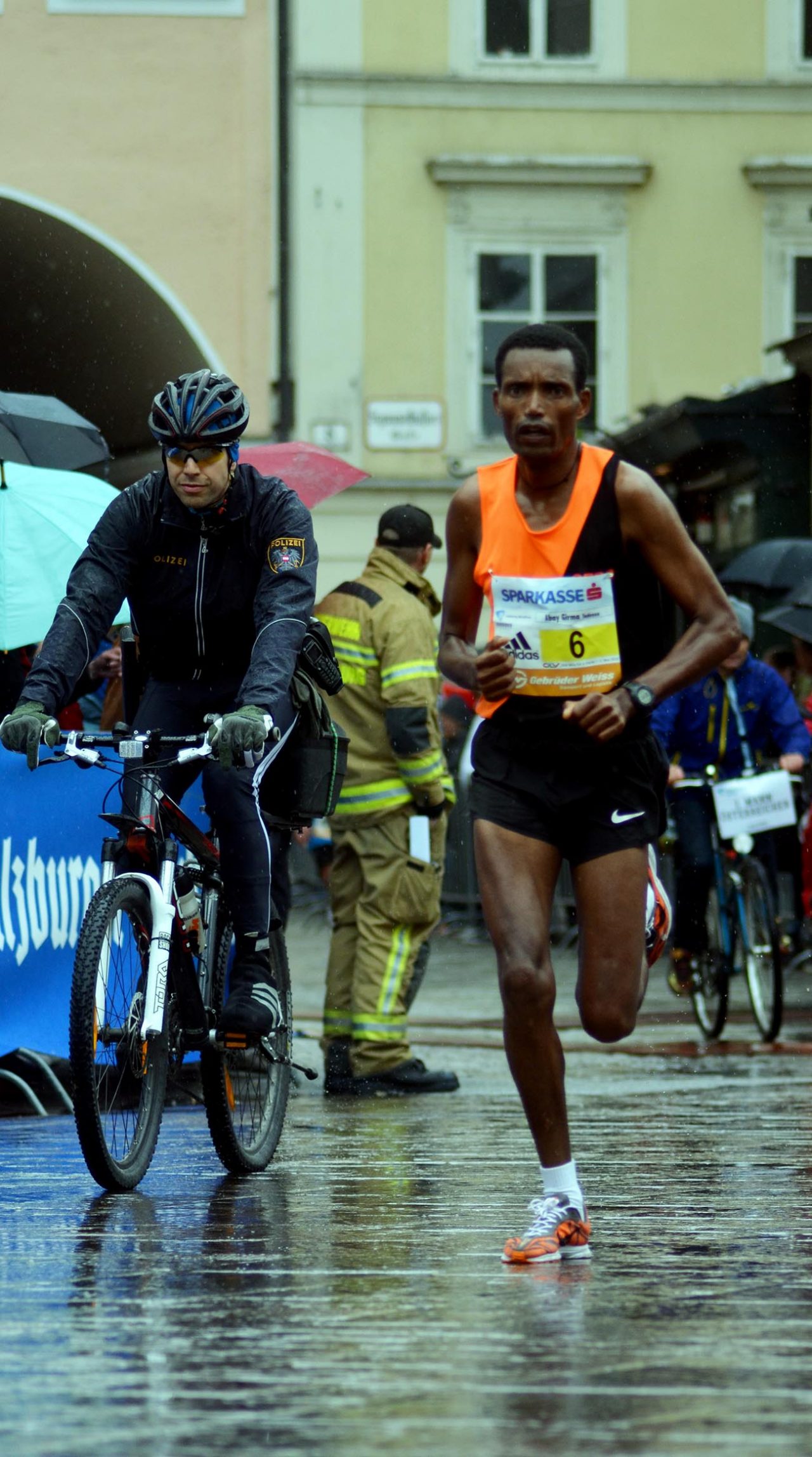 Top runner Temesgen Bekele shortly before crossing the finish line in Salzburg – accompanied by a bike-riding policeman. Even the cops travel in eco-friendly style! Photo: Buschmann