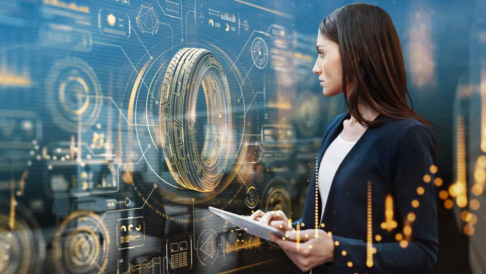 (Mujer mirando la pantalla con gráficos digitales y una rueda de vehículo en primer plano, sosteniendo una tablet. Tecnología e innovación.)