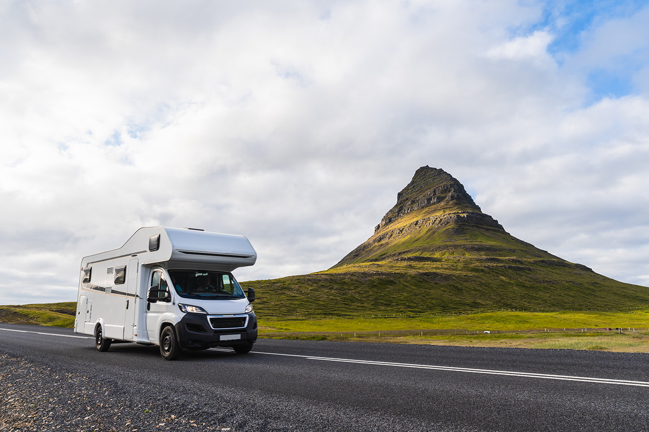Stock photo of a van passing across Kirkjufell Mountain in iceland. Rv in front on the road.