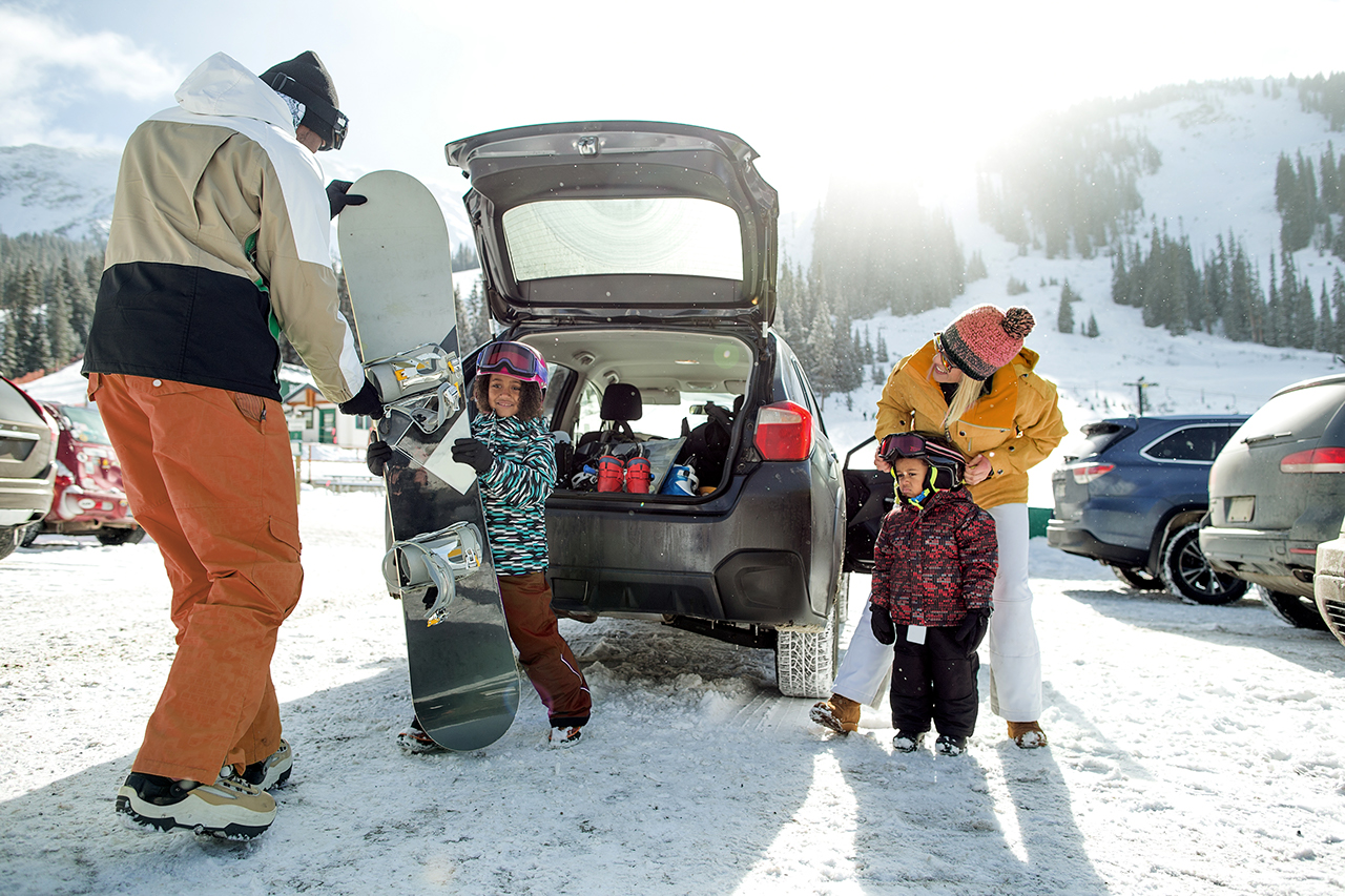 A family unloading their snowboard in winter landscape.