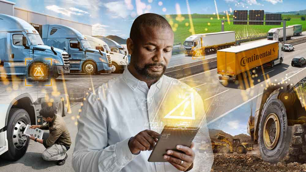 (Hombre usando una tableta en un entorno de transporte, con camiones y mantenimiento, simbolizando tecnología y logística.)