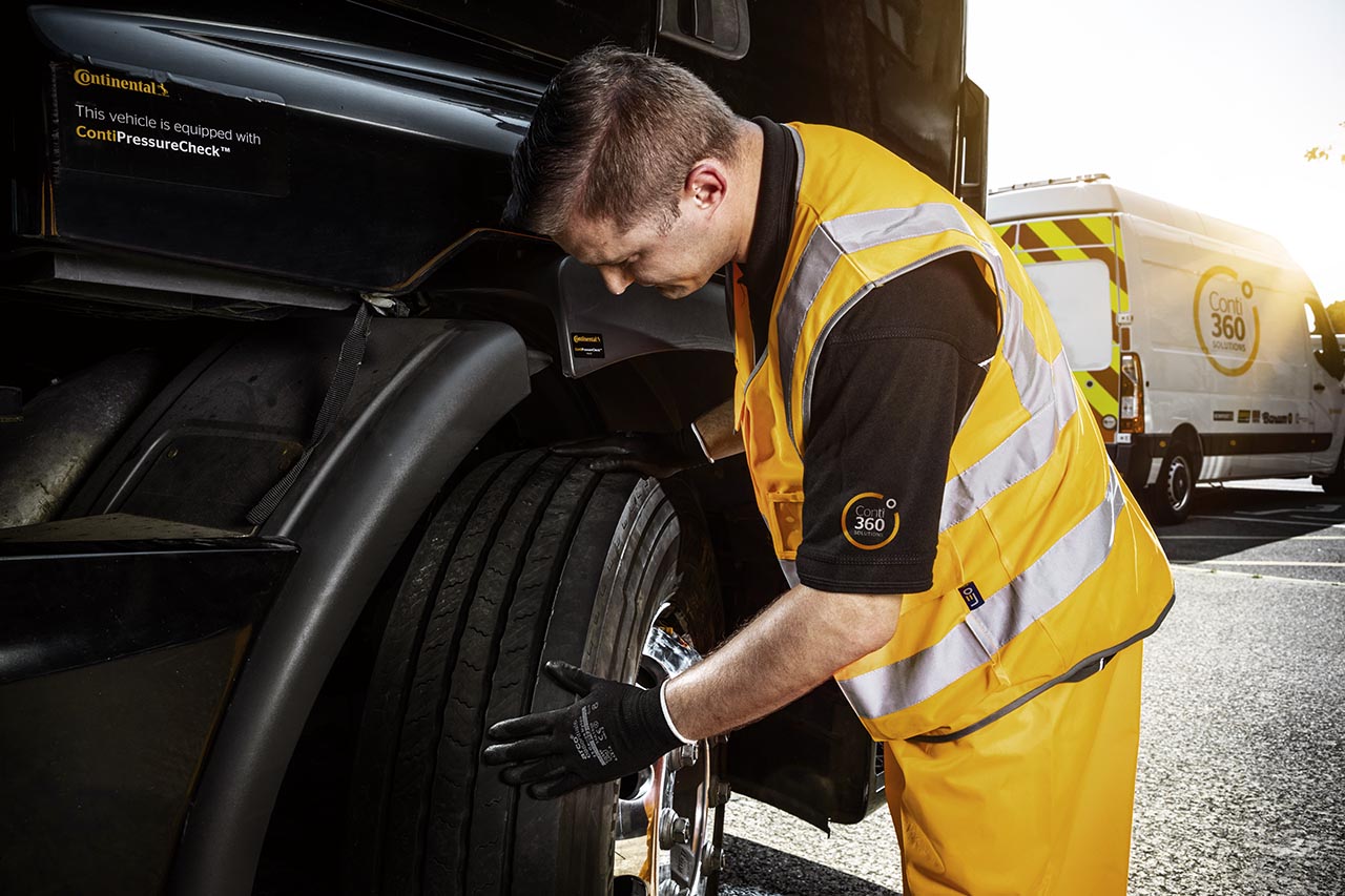 A man from the Conti360 Breakdown service inspects a truck tire