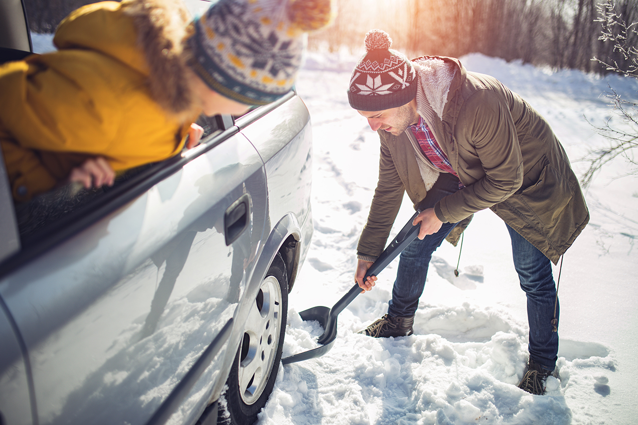 Shoveling snow A man cleans snow near the car with shovel in nature.
