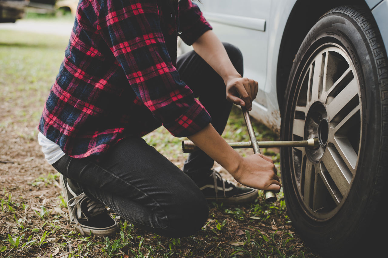 Young hipster woman checking out a flat tyre on her car try to fix., Young hipster woman checking out a flat tyre on her car try to f Entretien Pneu