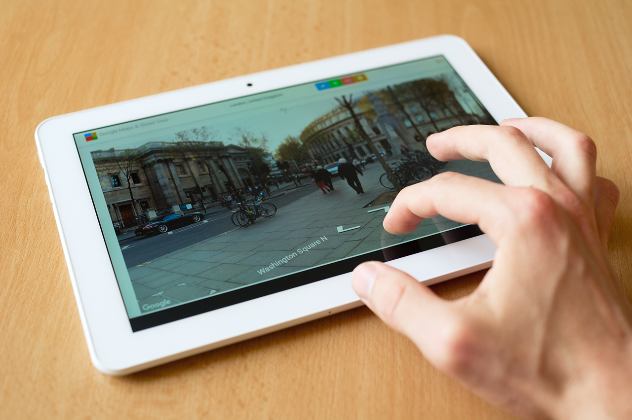 Tablet 사람의 손가락으로 태블릿을 사용하는 모습. 스트리트 뷰 홈페이지가 표시된 사진.