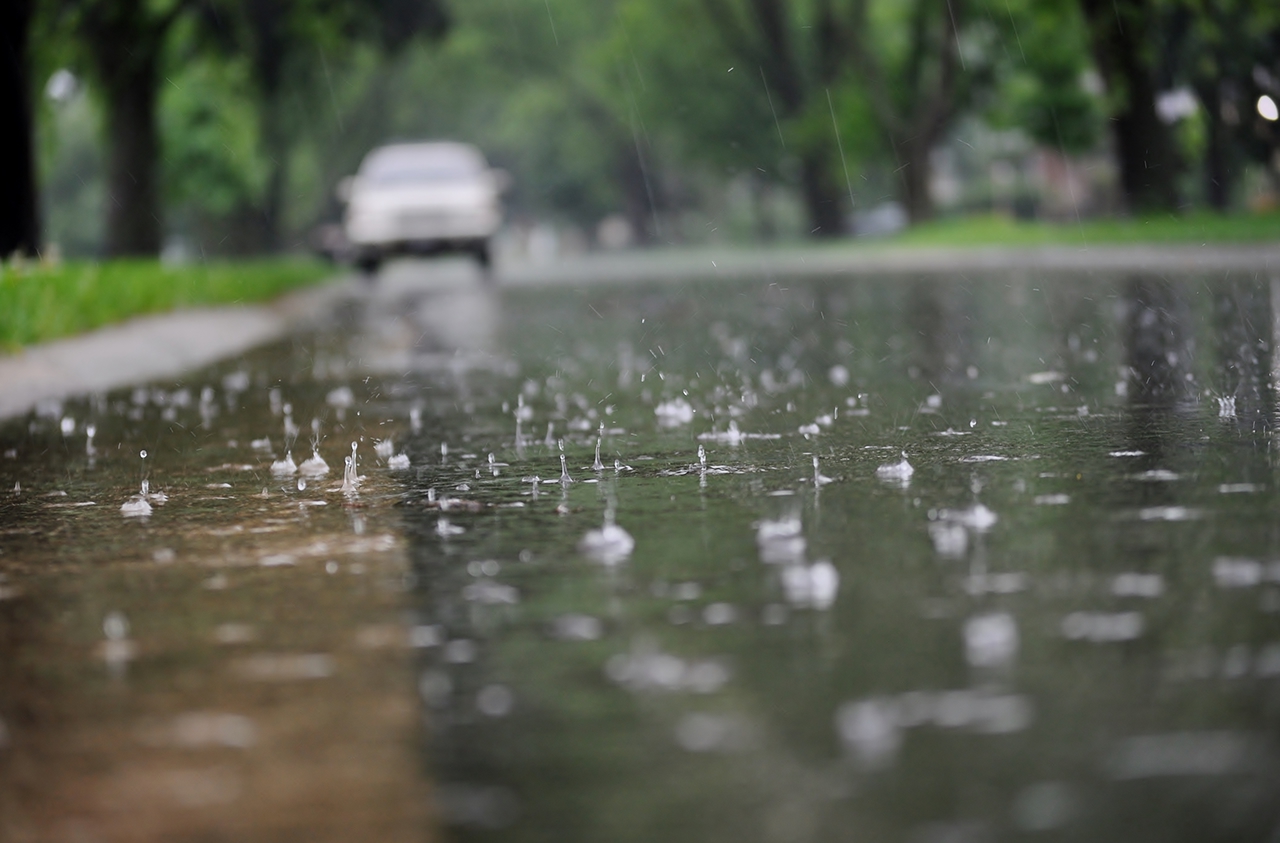 폭우가 내릴 때, 길의 연석(도로 경계석)을 따라 흐르는 물. 튀는 빗방울과 공기 방울 클로즈업.