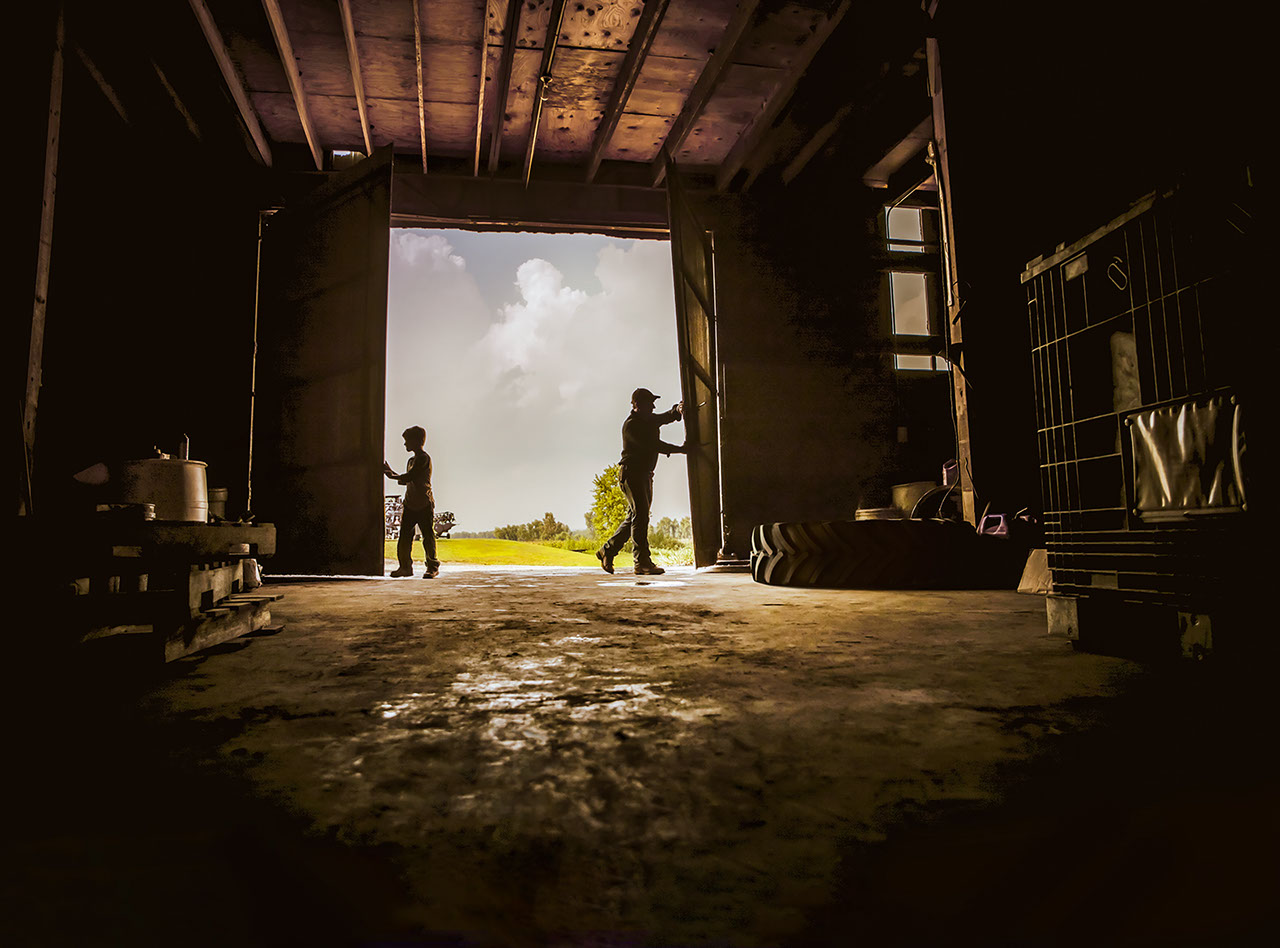 Farmers open the door of a barn