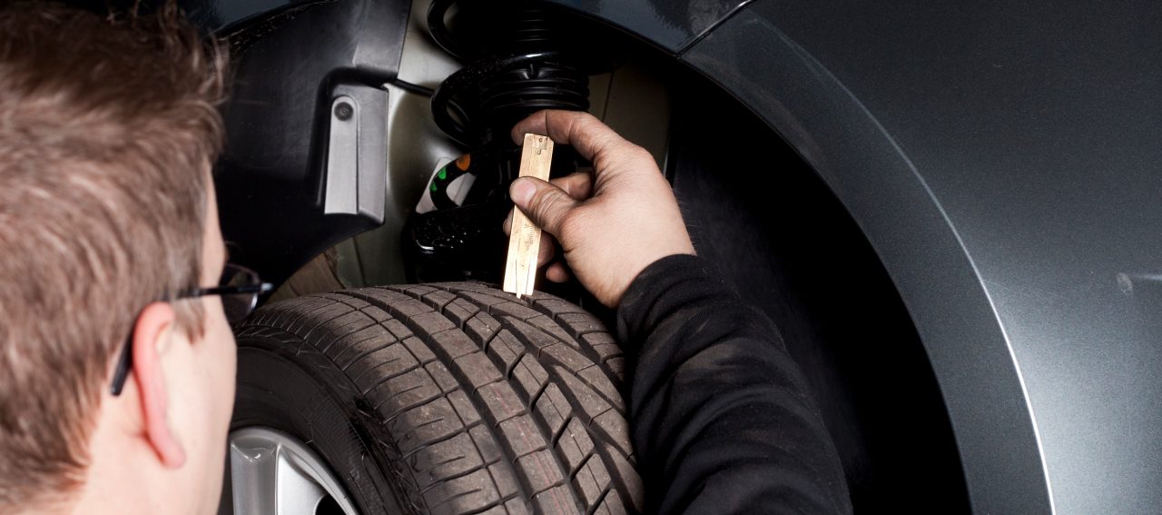 Mechanic is checking the tread depth of a tire.