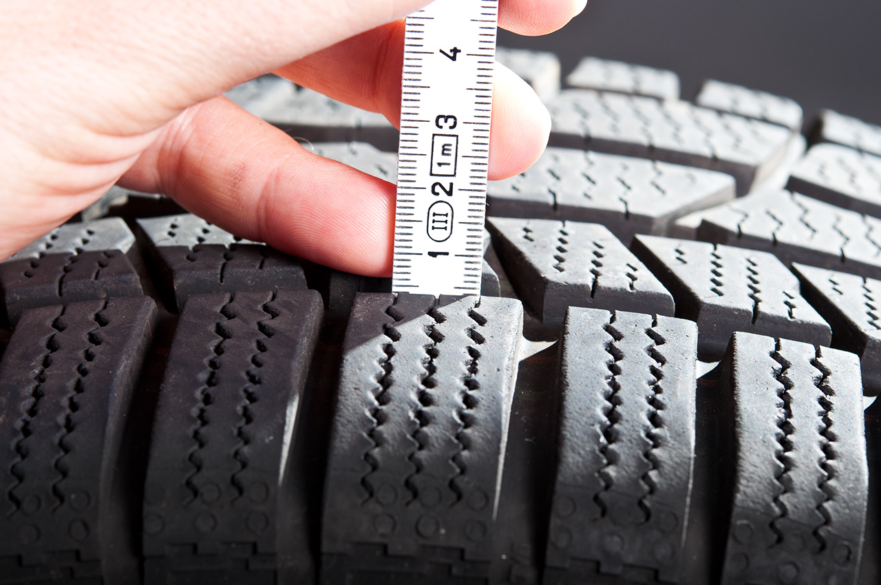 Woman checking a tire´s tread depth