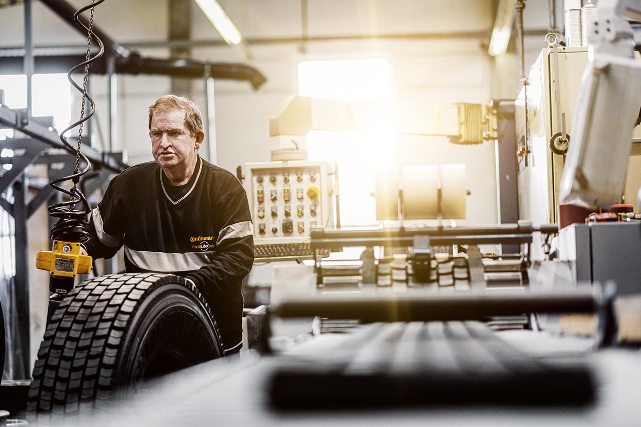 Homem a transportar pneu para ser recauchutado