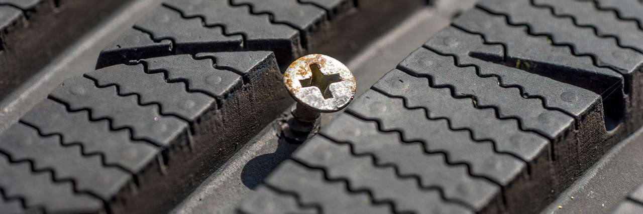 Parafuso preso num pneu, indicando um furo.