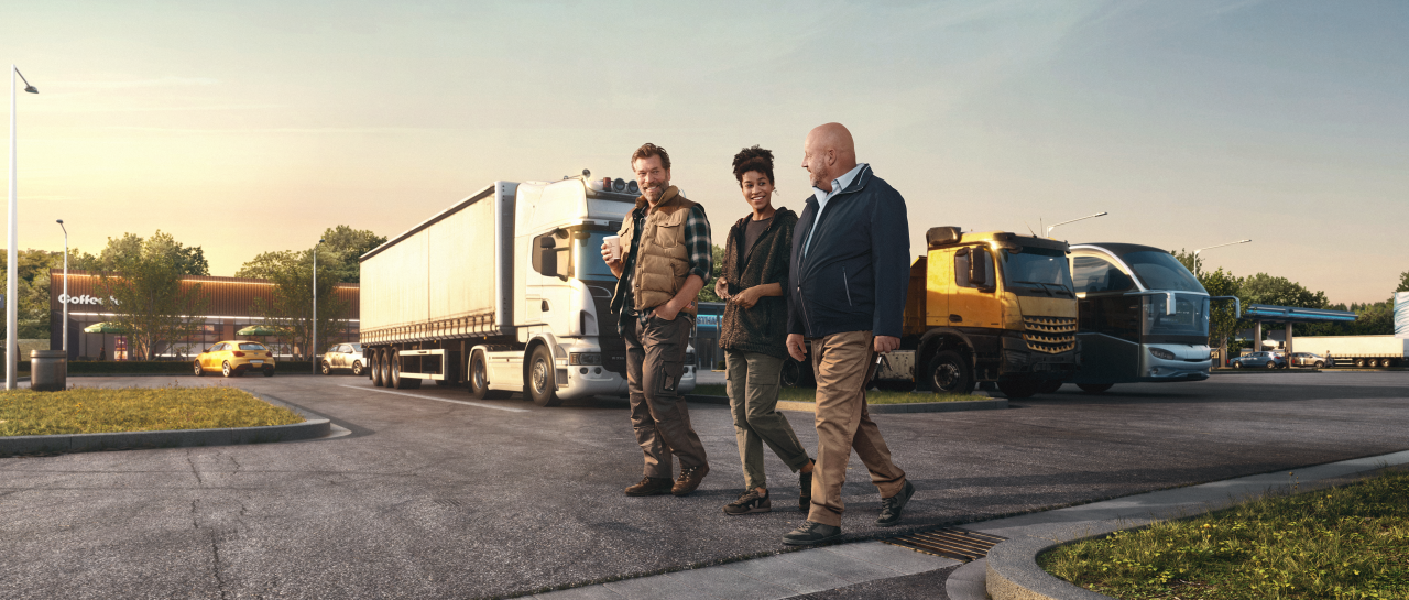Three persons walking at a truck stop.
